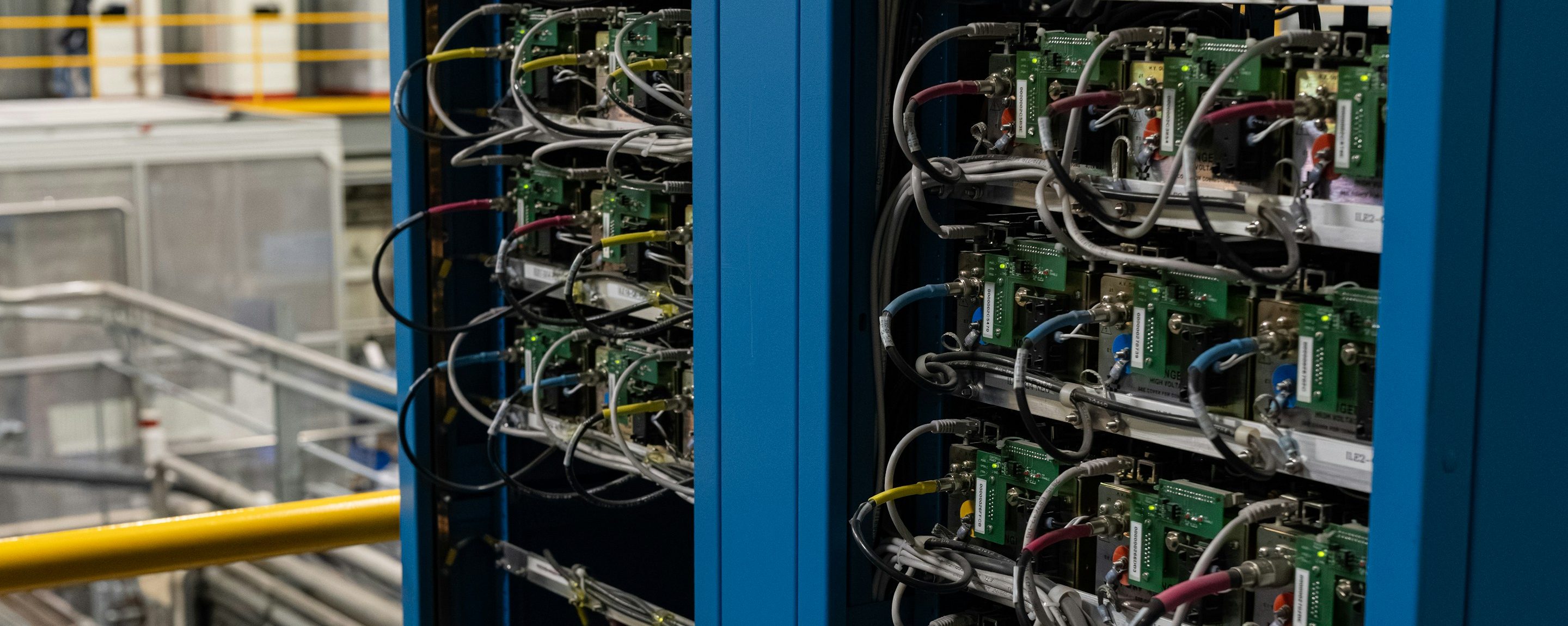 An open equipment rack packed with wiring and control modules in an industrial plant room