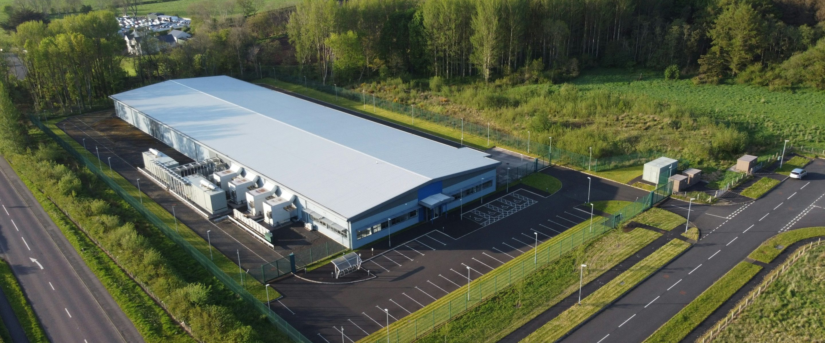 A data center building photographed from the air, seen with its access road and plant yard