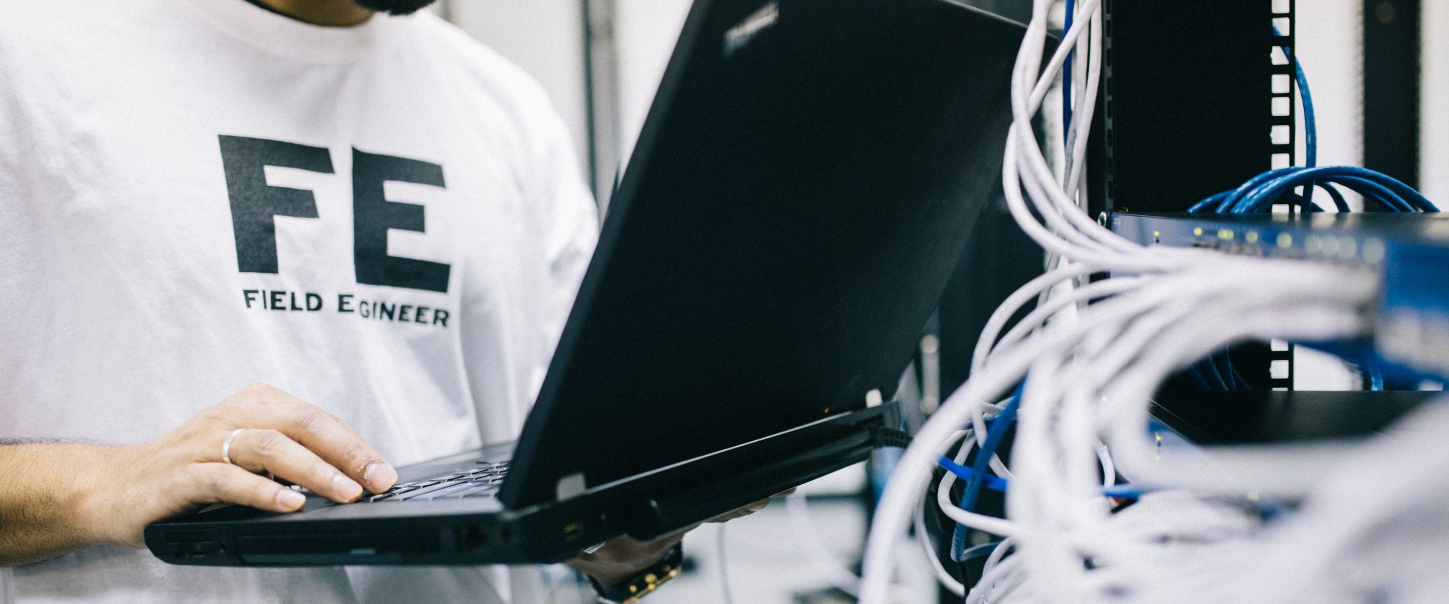 A field engineer checking cabling against a laptop in a data hall
