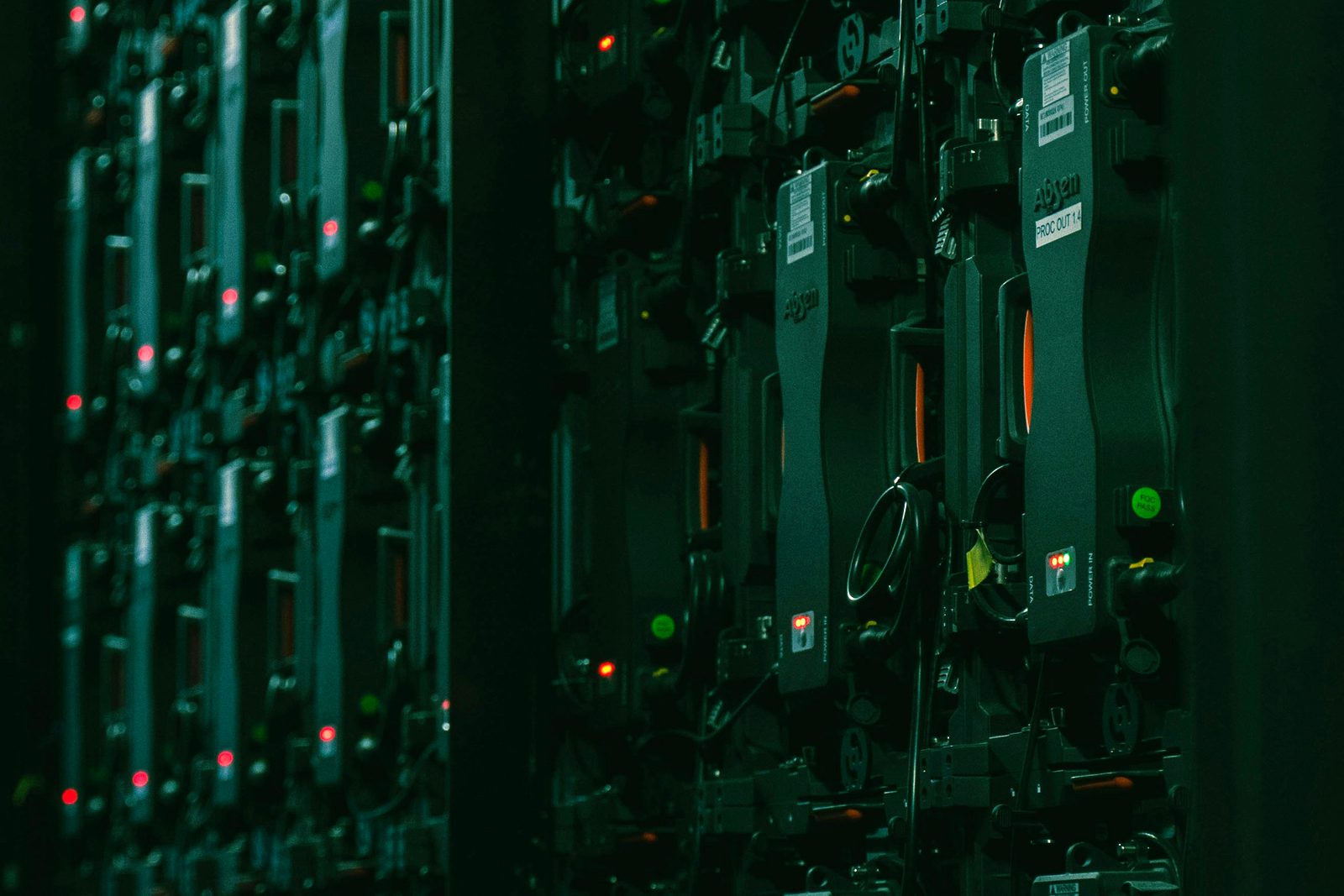 A densely populated equipment rack in near-darkness, lit only by red and green status indicators