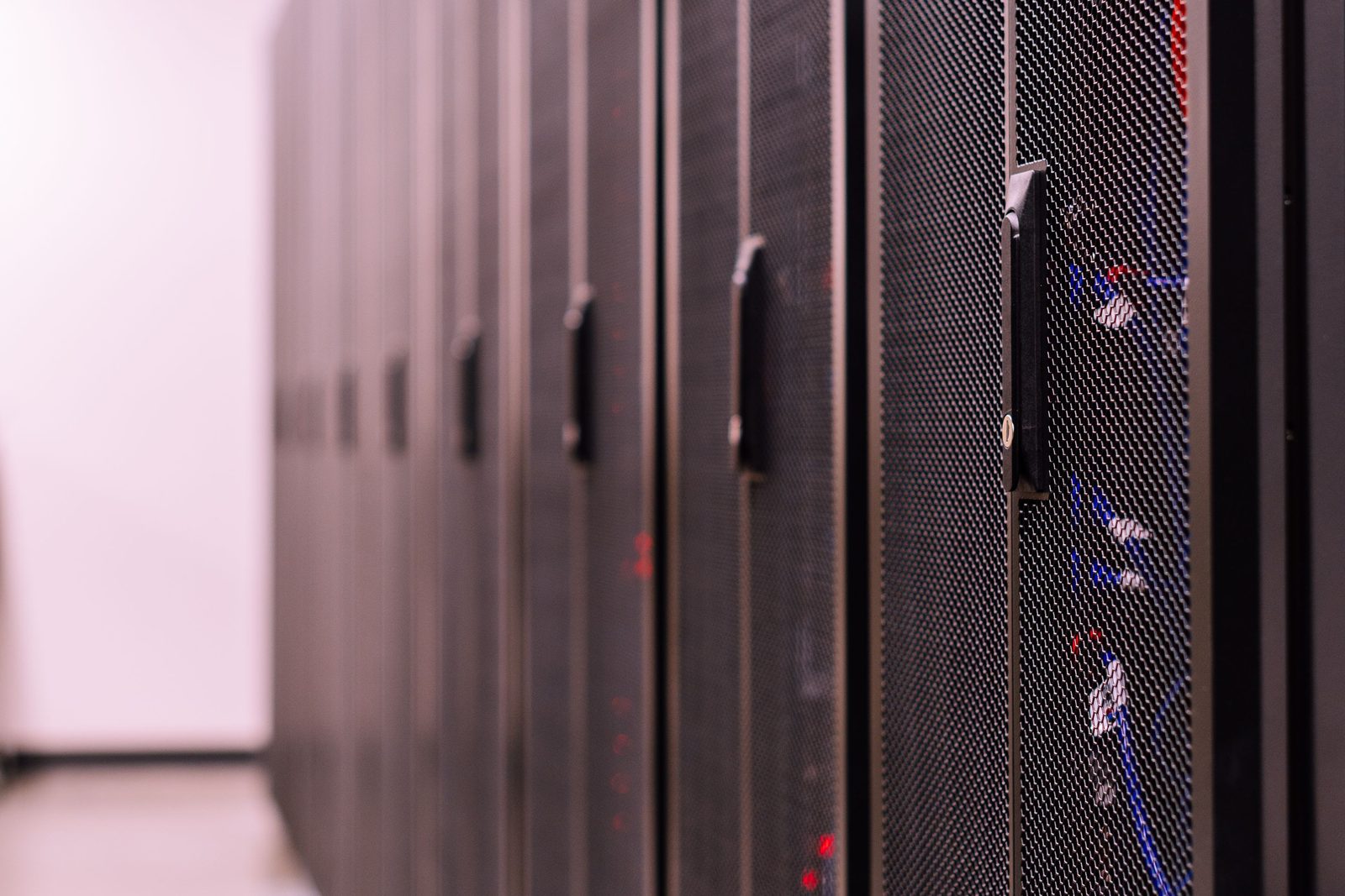 A row of locked equipment cabinets receding down a controlled data hall corridor