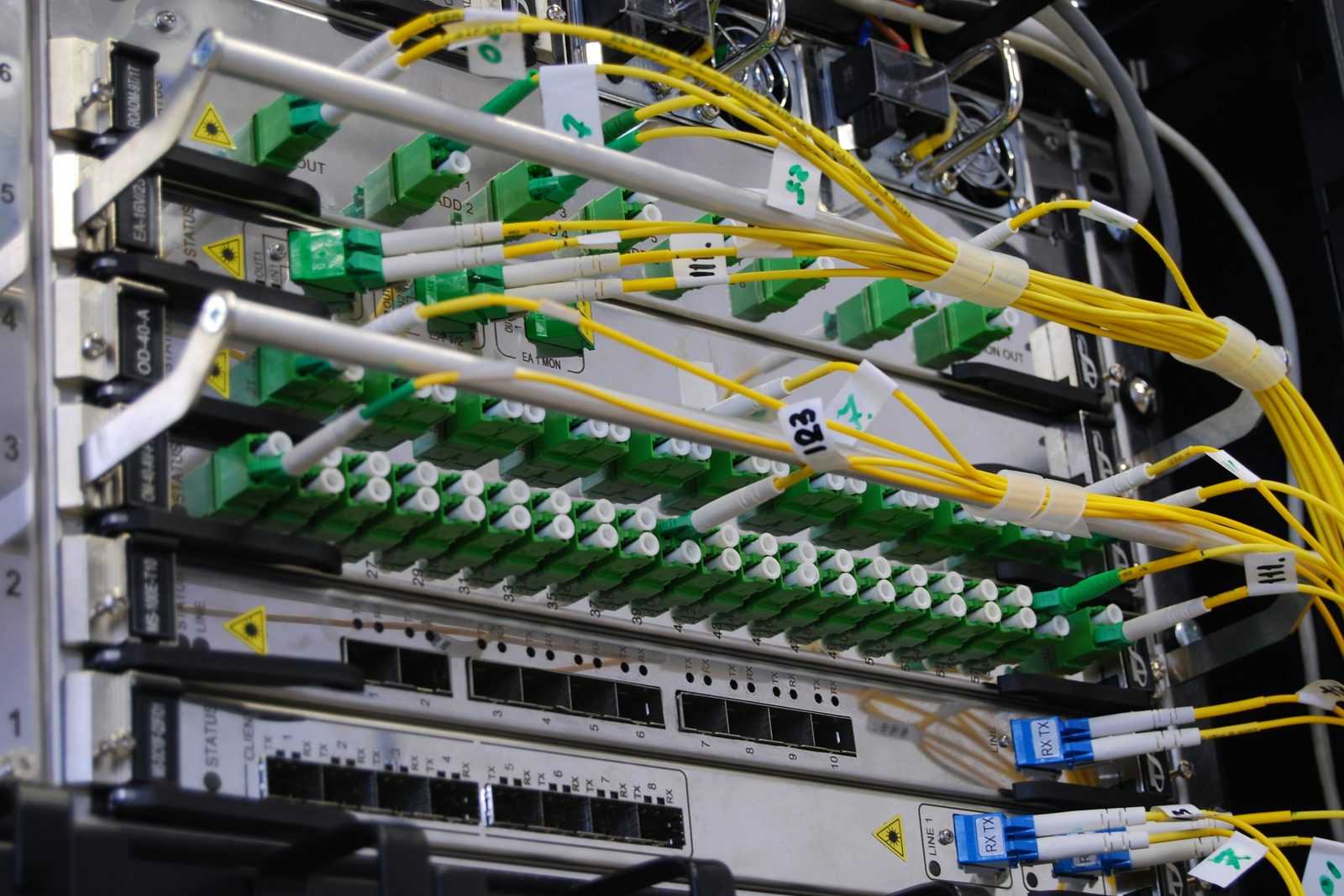 A labelled fibre distribution frame with green connectors, yellow patch leads and numbered ports