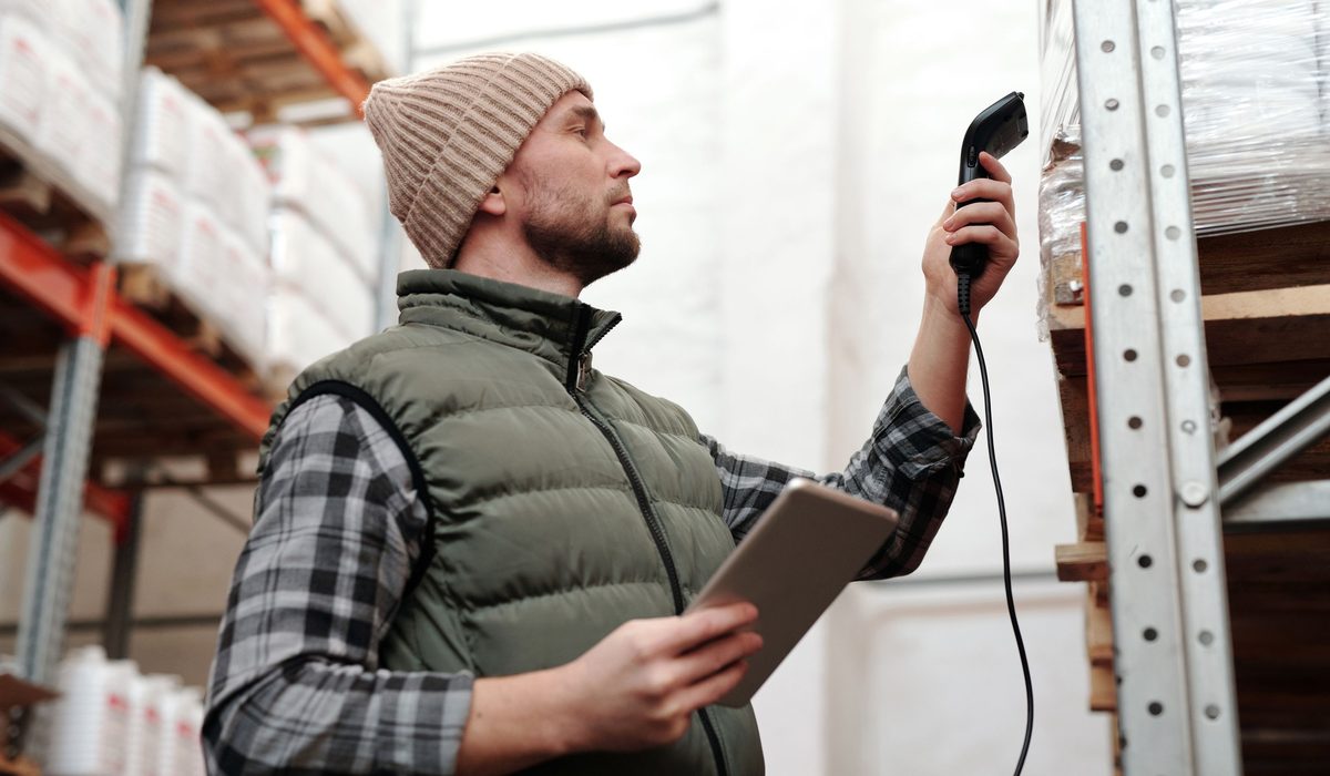 A technician scanning stock with a handheld reader while holding a tablet