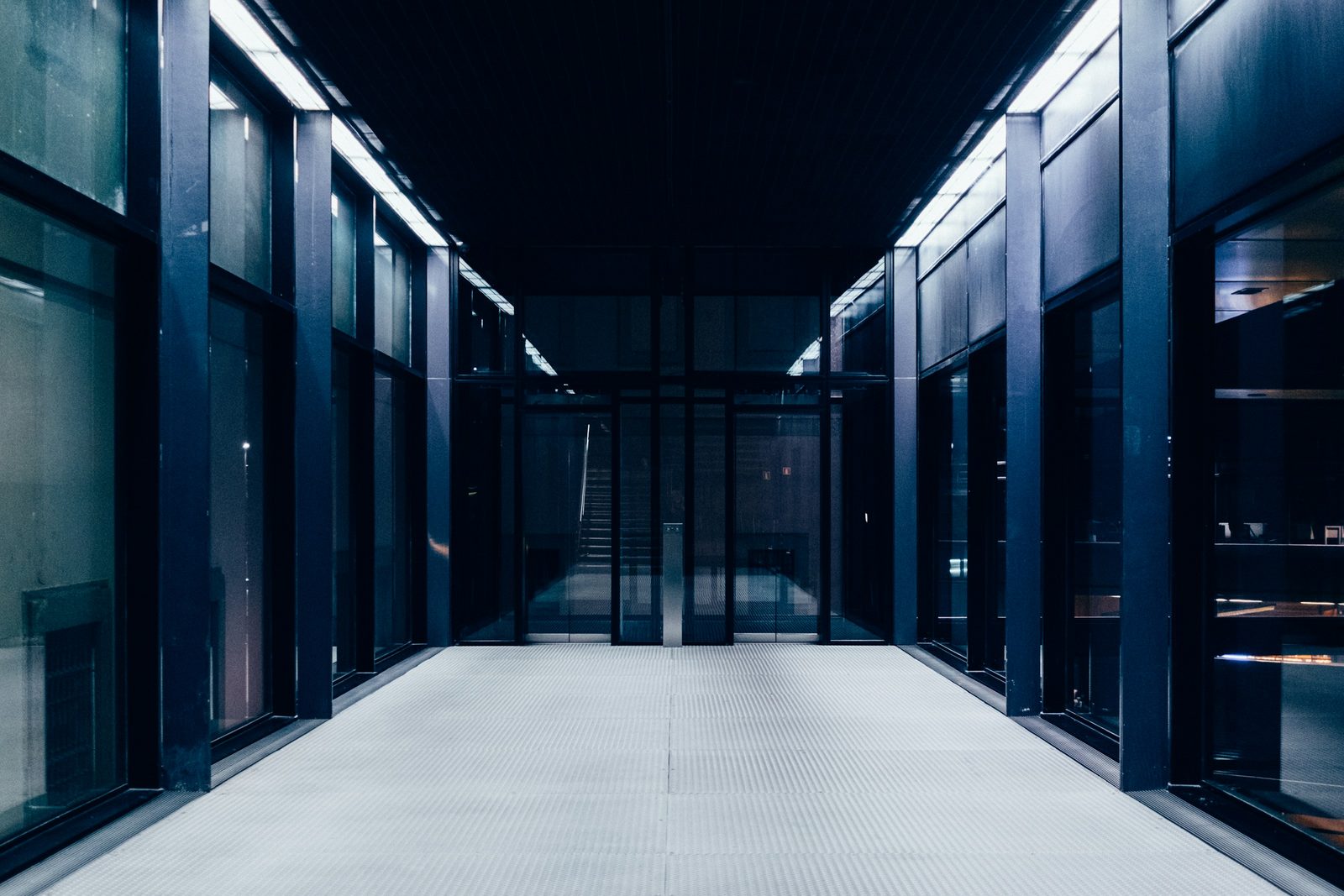 A corridor between glass-fronted cabinet enclosures in a data hall