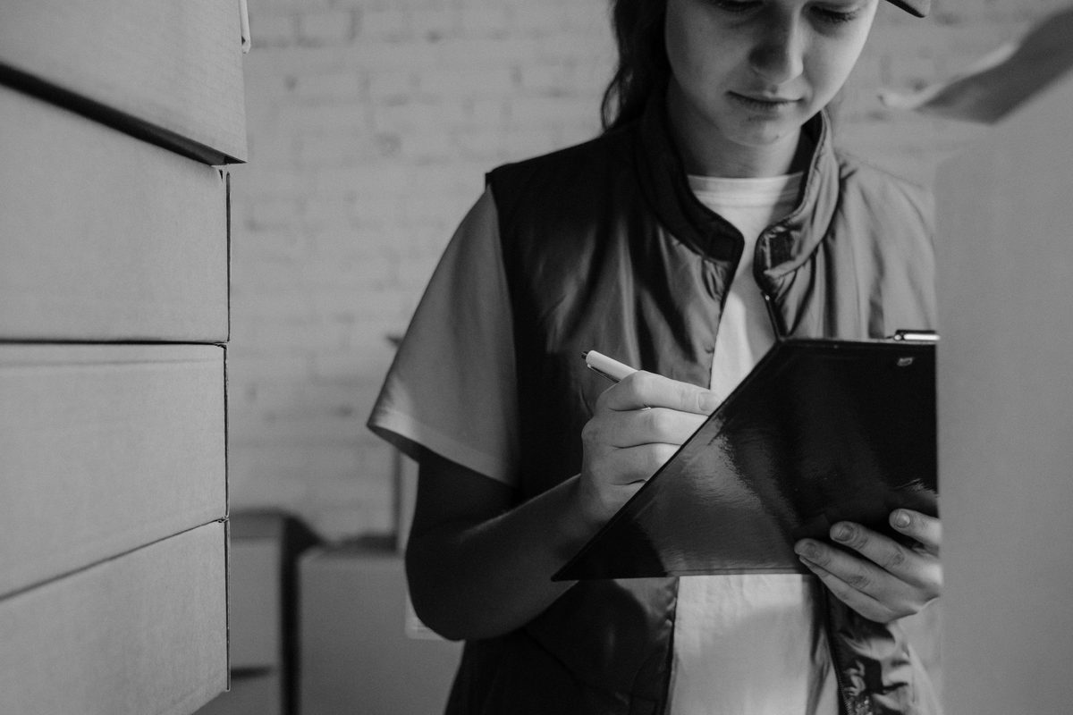 An auditor working through a written record against stored equipment