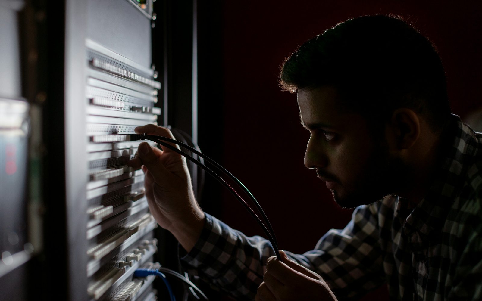 An engineer tracing a cable at a patch panel by the light of the rack