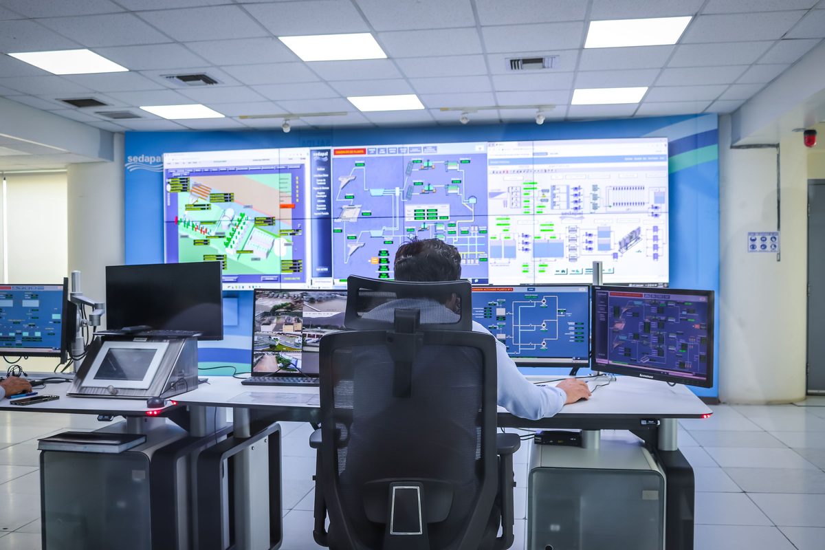 An operator watching live infrastructure dashboards from a control-room desk