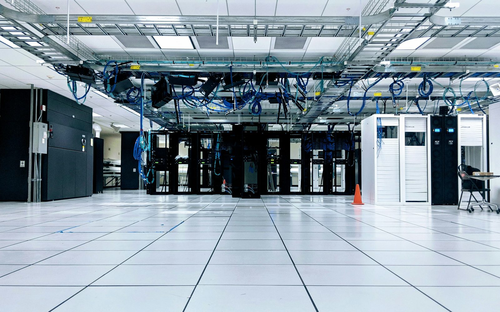 An open data hall floor with cabinet rows and overhead cable tray
