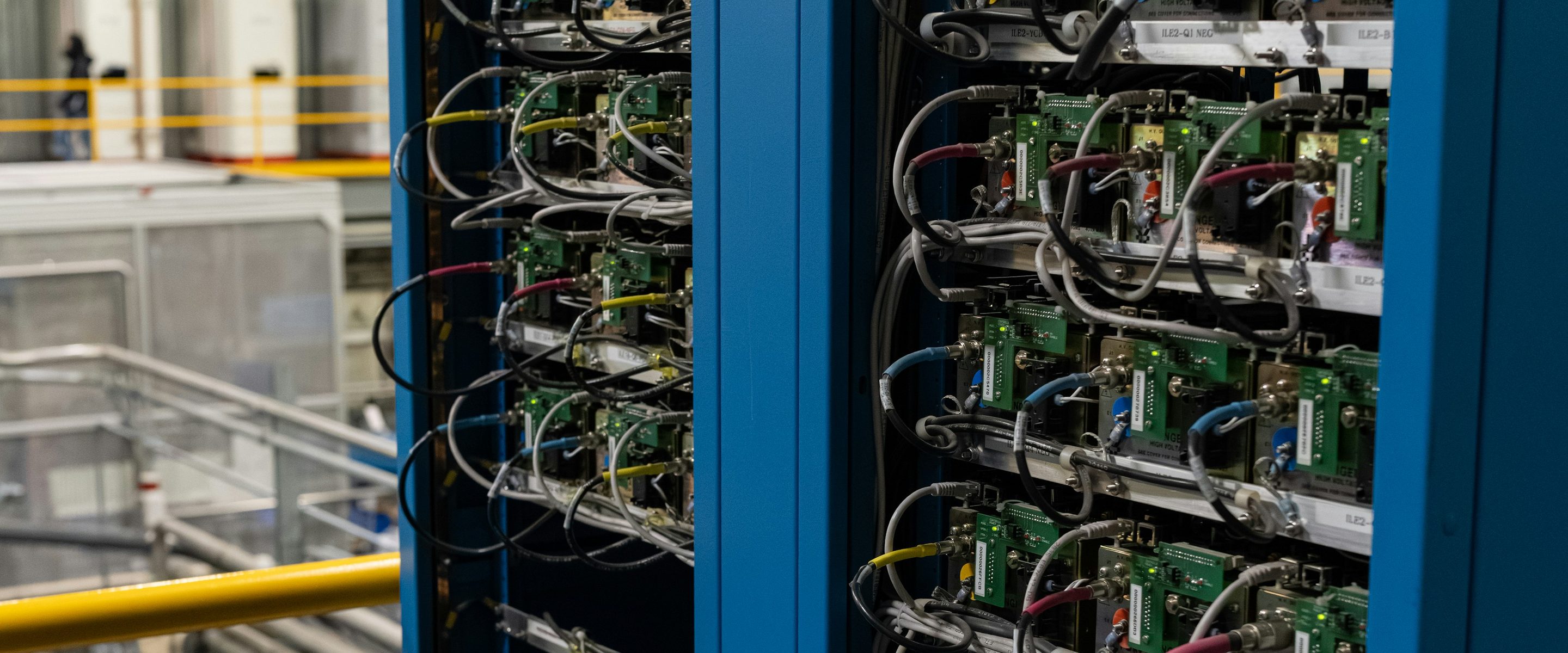 Tall equipment cabinets on a plant floor, packed with boards, wiring and labels