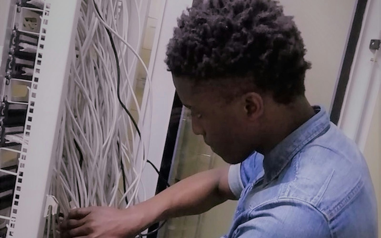 An engineer working by hand at a wiring frame packed with white cabling