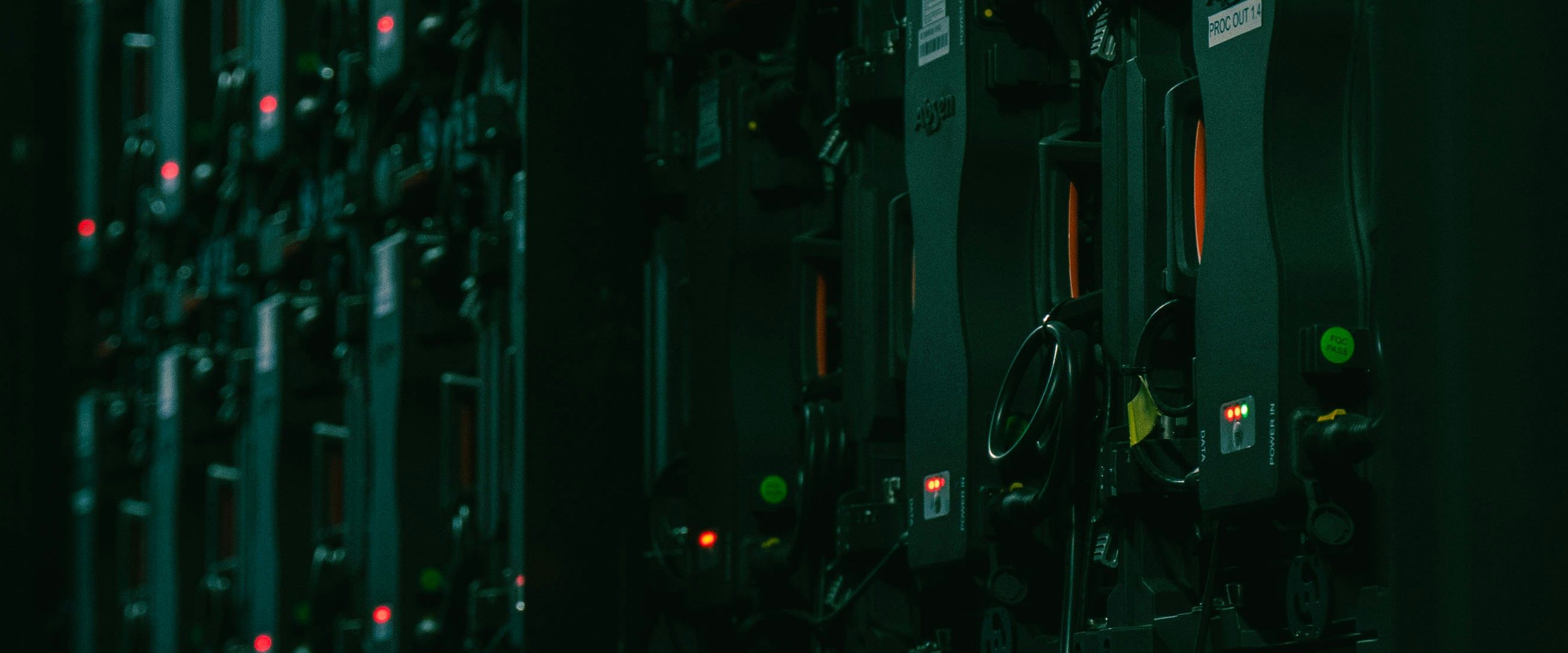 Rows of rack-mounted equipment in a darkened hall, picked out by red and green indicator lights