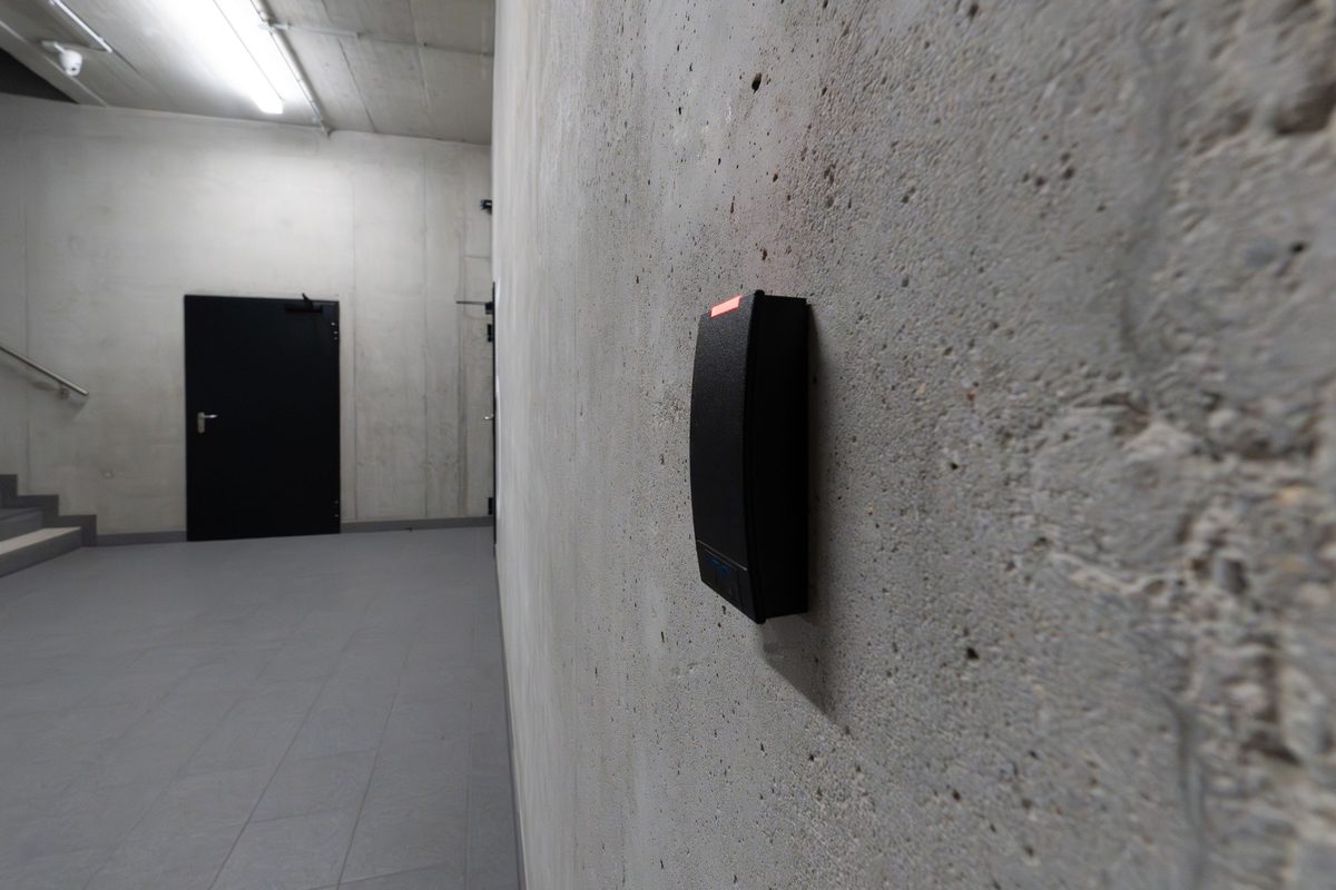 An access-control reader beside a secured door in a facility corridor