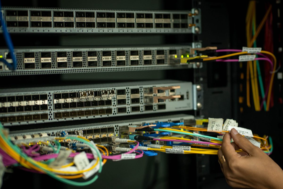 A technician handling labelled patch leads at a switch during a change