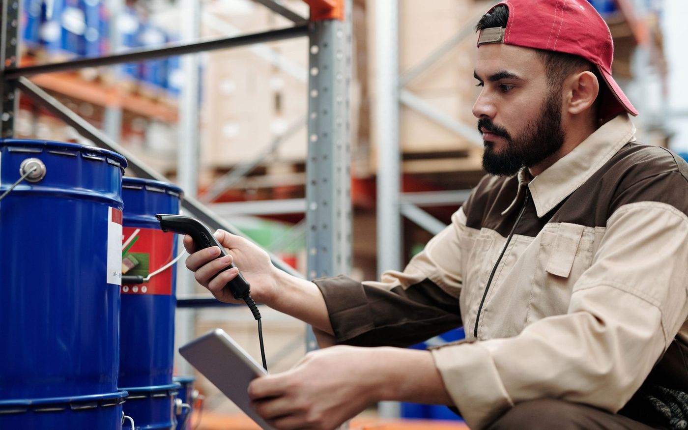A warehouse worker checking stock on the shelves with a handheld scanner