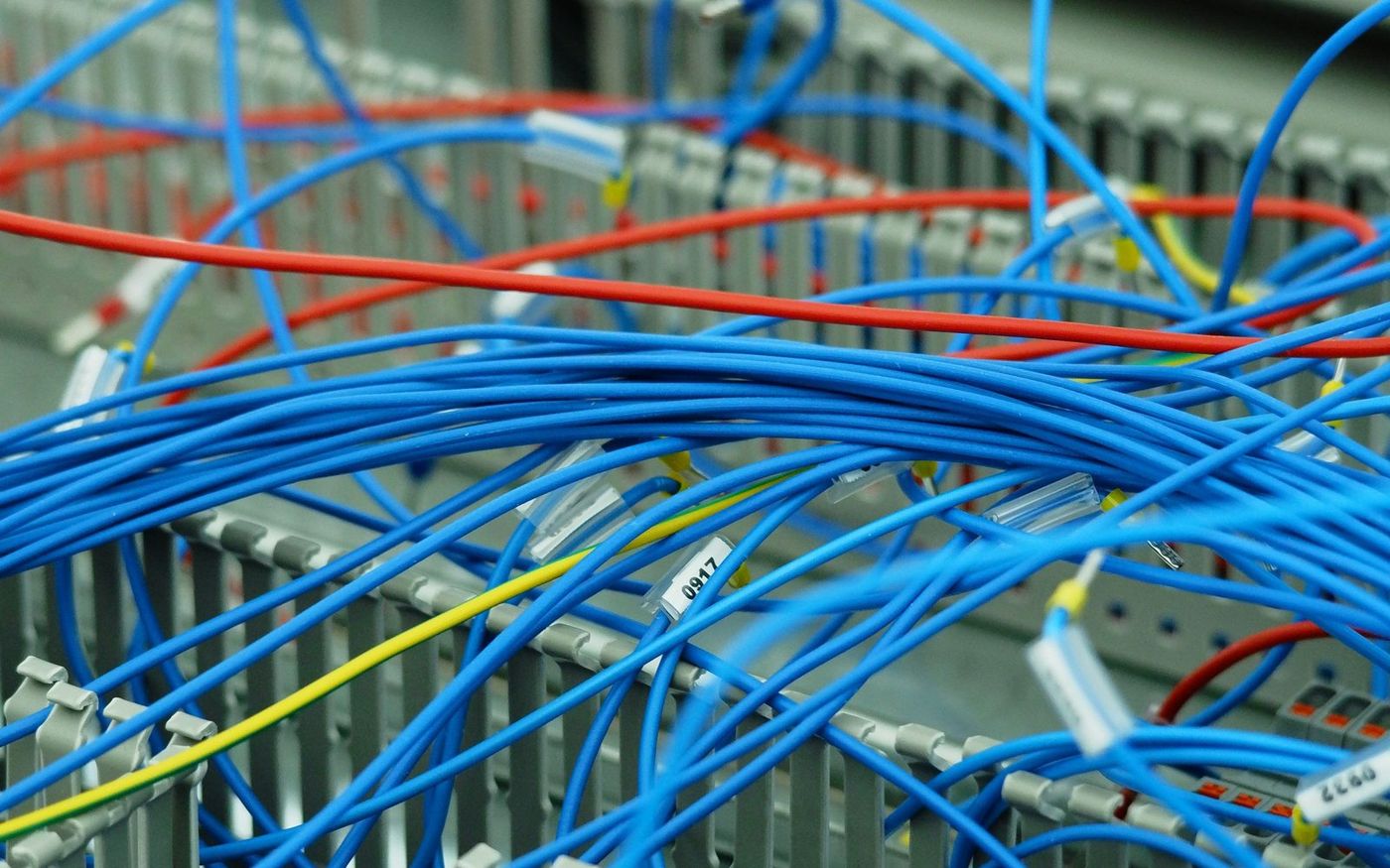 Dense patch cabling with handwritten cable labels, the kind of wiring a manual audit has to trace by hand
