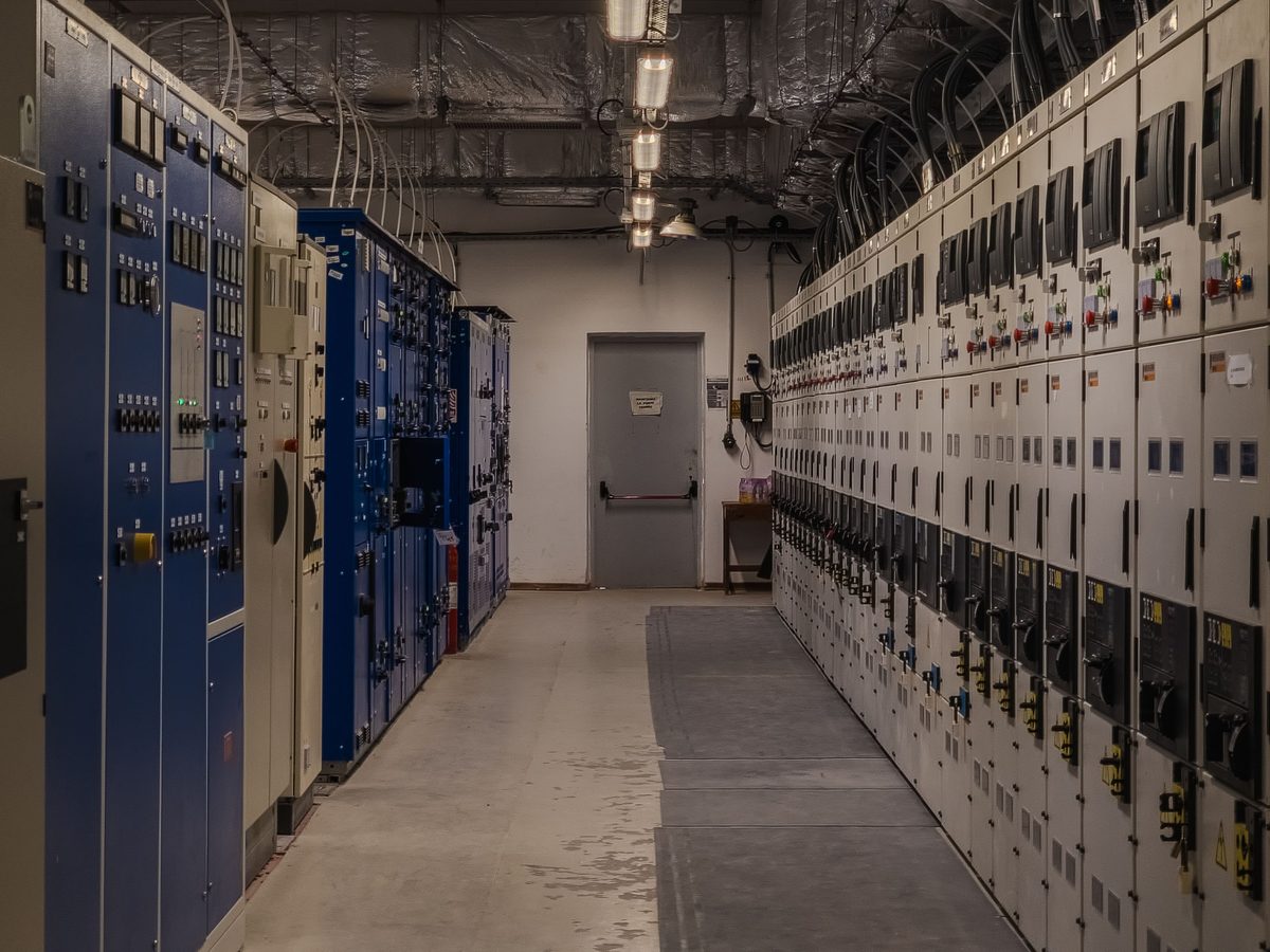 A plant corridor lined with facility control panels inside a data centre