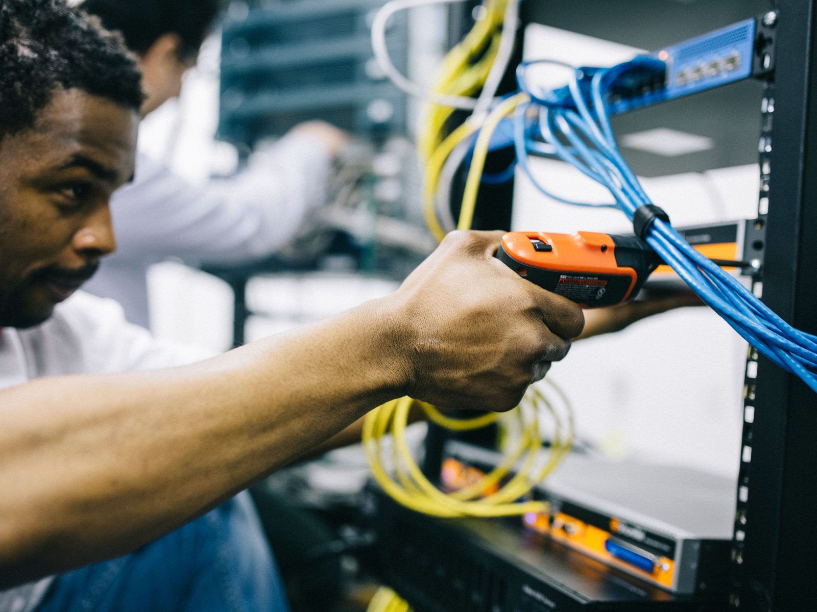 An engineer inspecting cabling at the front of a rack during a facility review